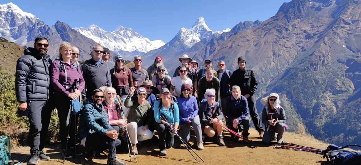 Guided group of solo travelers and trekkers posing together on a Himalayan trail near Dharamshala, Himachal Pradesh, emphasizing safety, group support, and guided trekking in India.